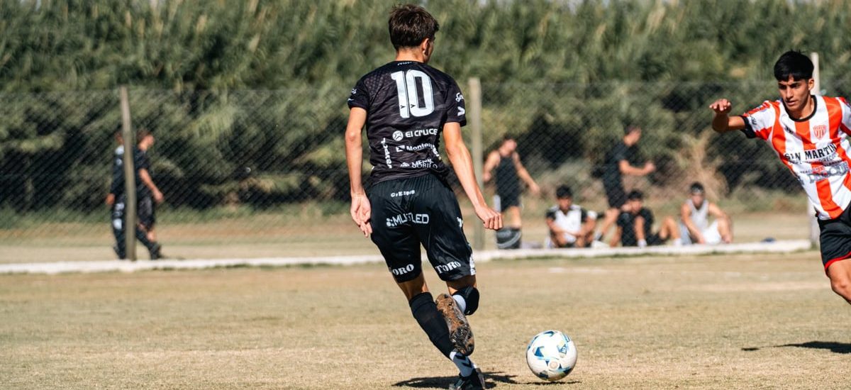 A dynamic soccer scene with young athletes striving for the ball in a local match outdoors.