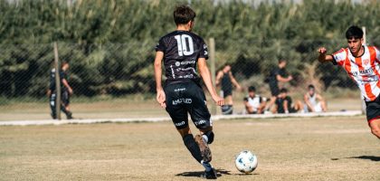 A dynamic soccer scene with young athletes striving for the ball in a local match outdoors.