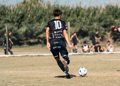 A dynamic soccer scene with young athletes striving for the ball in a local match outdoors.